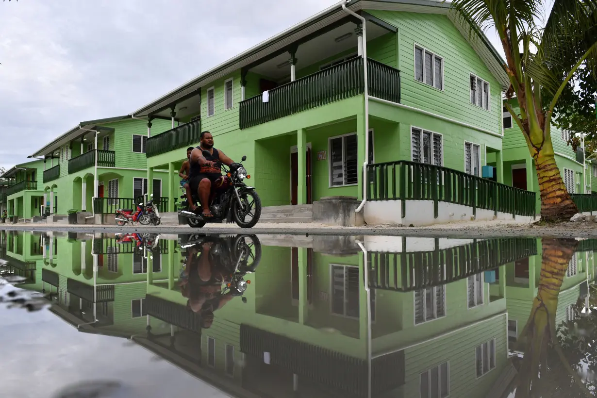 A man riding a motorbike is seen reflected in a puddle of water in Funafuti, Tuvalu,