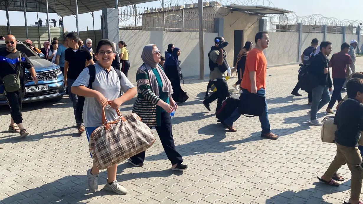 Palestinians with dual citizenship walk at the Rafah border crossing with Egypt, in the hope of getting permission to leave Gaza