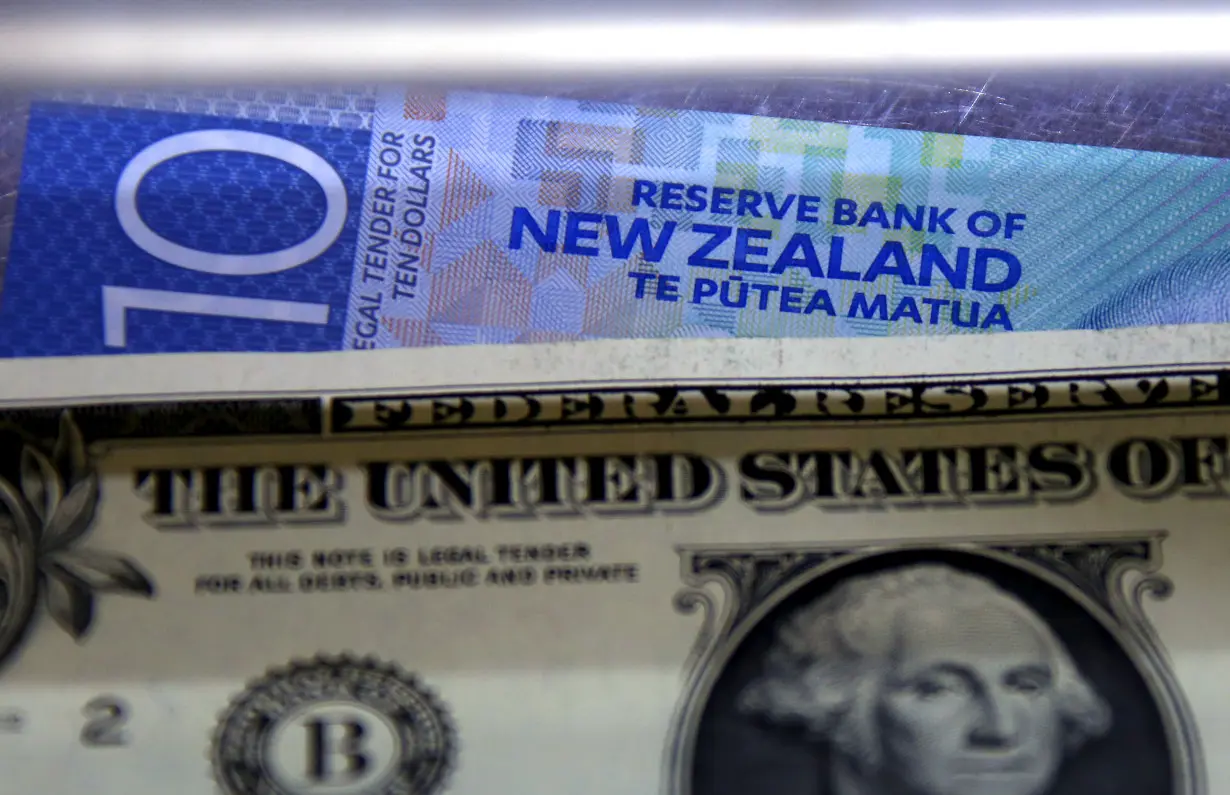 A New Zealand ten dollar note sits underneath a United States one dollar bill in the window of a currency exchange teller in Sydney, Australia