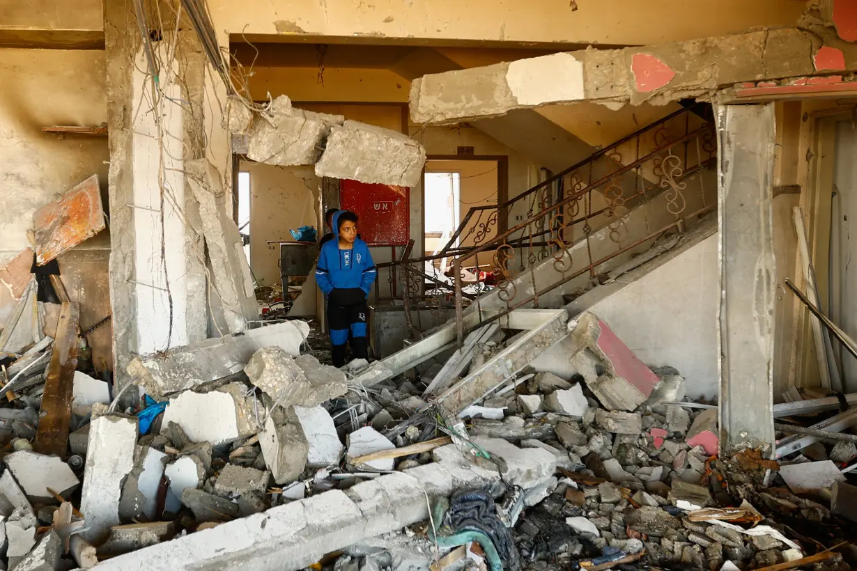 A boy walks among debris at the site of an Israeli strike on the apartment building, in Khan Younis