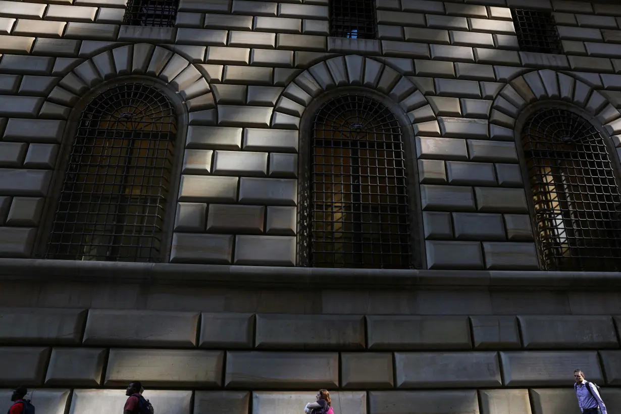 FILE PHOTO: People walk by the Federal Reserve Bank of New York in the financial district of New York City