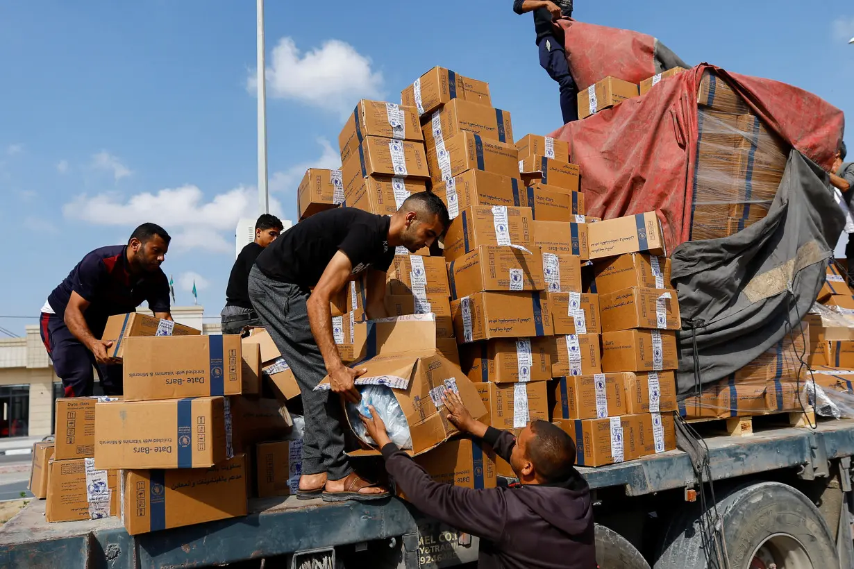 Palestinians reload a truck with aid that fell from the vehicle, in Rafah