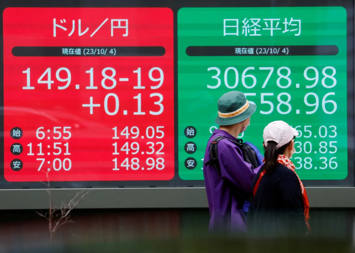 A man looks at an electric monitor displaying the Japanese yen exchange rate against the U.S. dollar and Nikkei share average in Tokyo