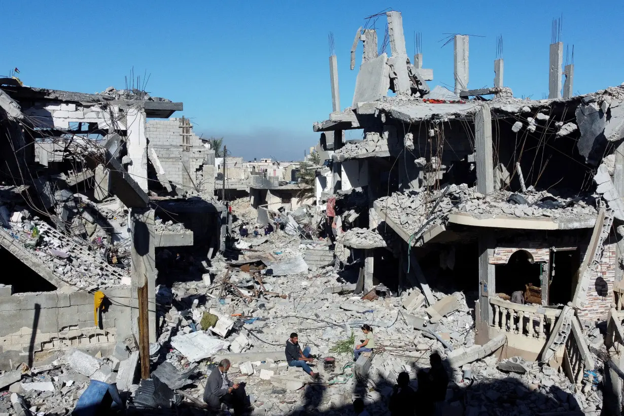 Palestinians cook among the houses destroyed in Israeli strikes, at Khan Younis refugee camp