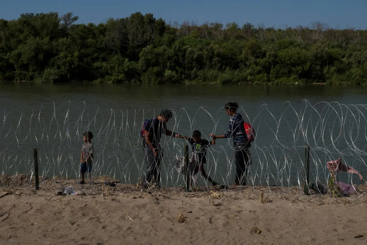 Migrant family navigates bank of Rio Grande river in Eagle Pass