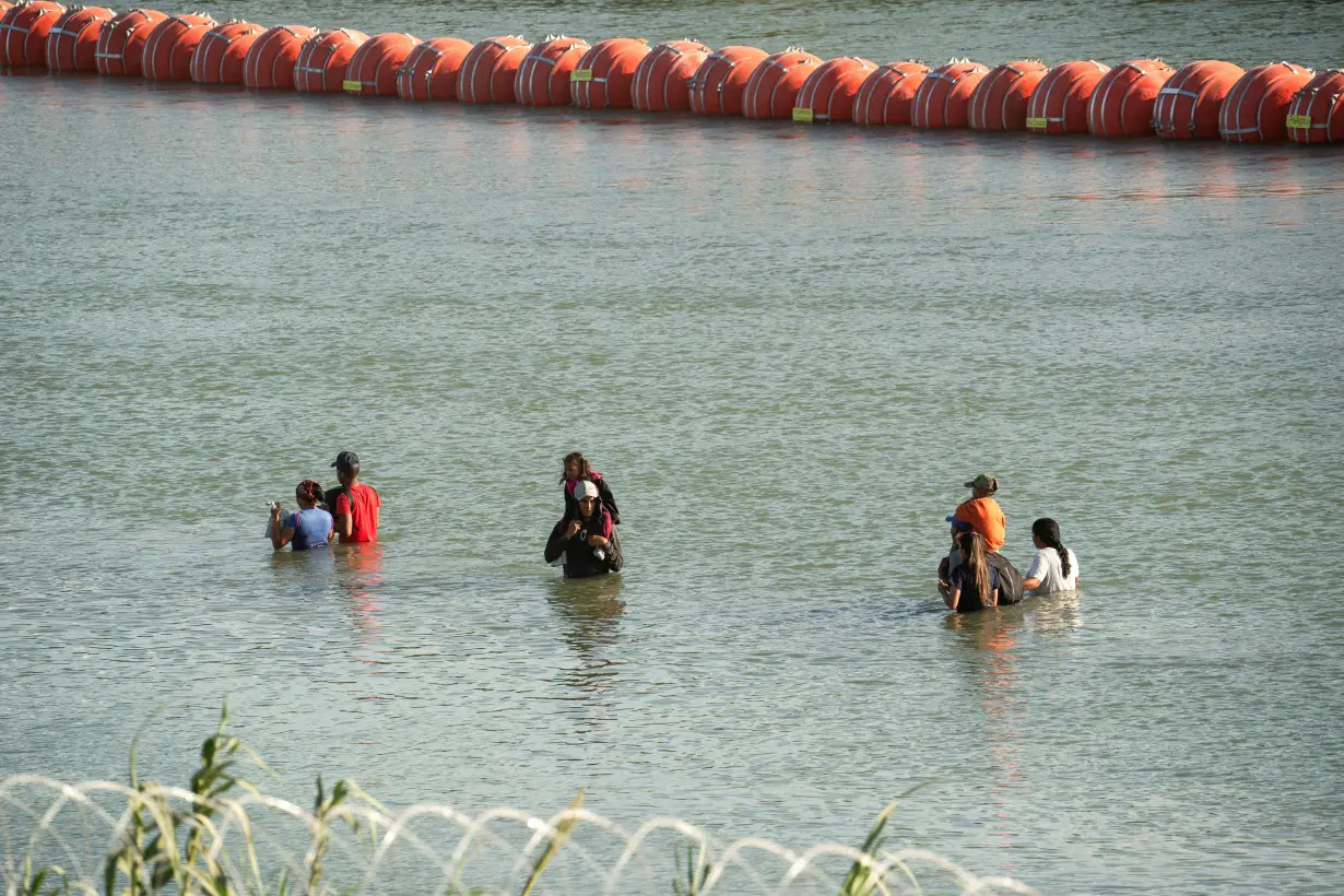 FILE PHOTO: Asylum-seeking migrants cross the Rio Grande river in Eagle Pass