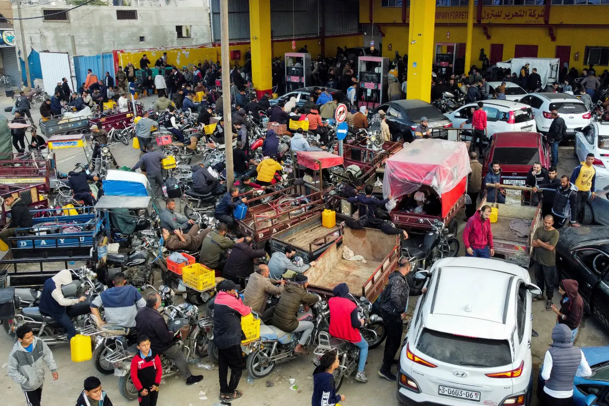 Palestinians wait to fill their cars with fuel, in Khan Younis