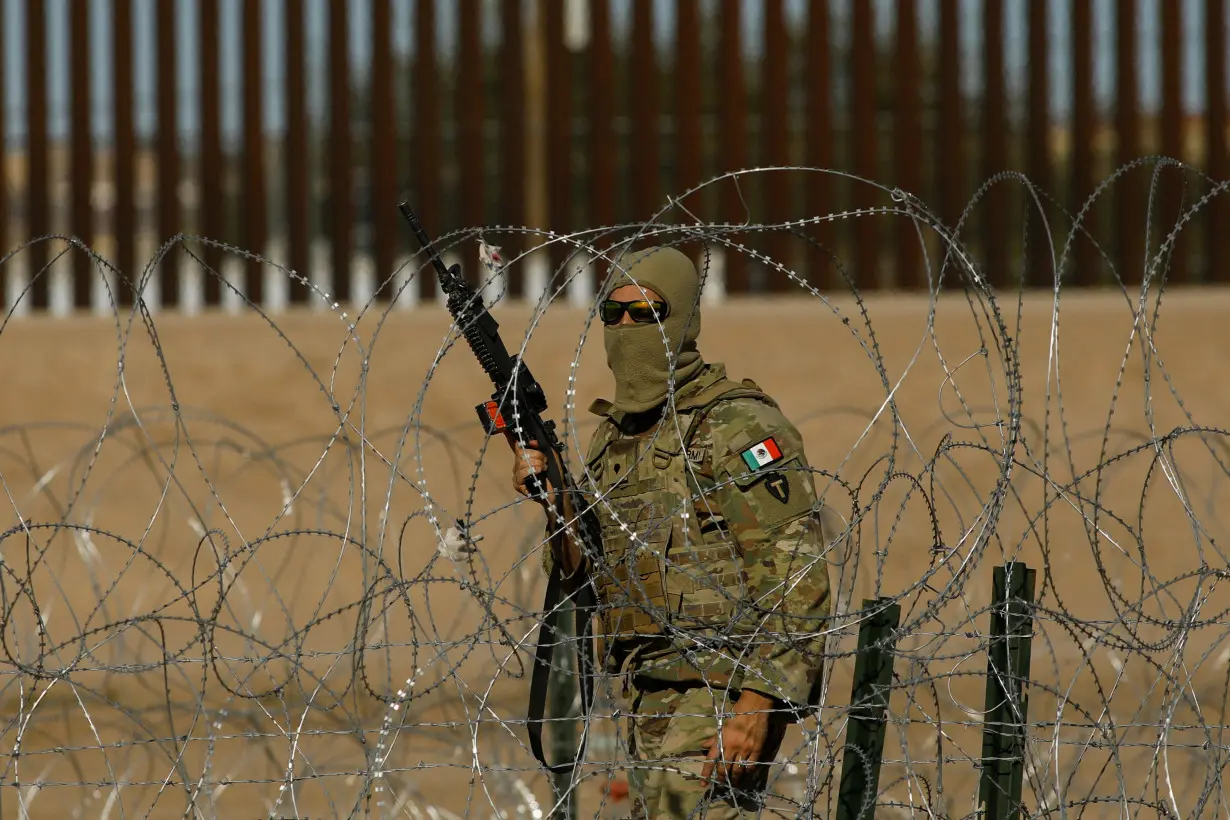 A member of the Texas National Guard stands guard on the banks of the Rio Bravo river, as seen from Ciudad Juarez