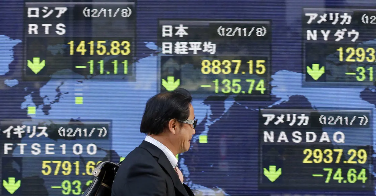 A man passes an electronic board displaying falls in global market indices outside a brokerage in Tokyo