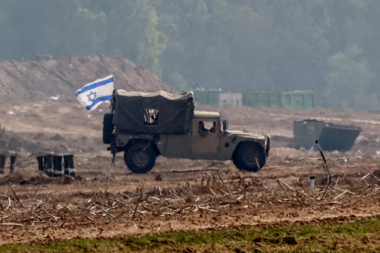 Israeli military vehicles operate at the border with Gaza as seen from southern Israel