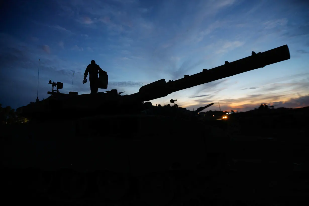 An Israeli soldier walks on an Israeli tank near the Israel-Gaza border