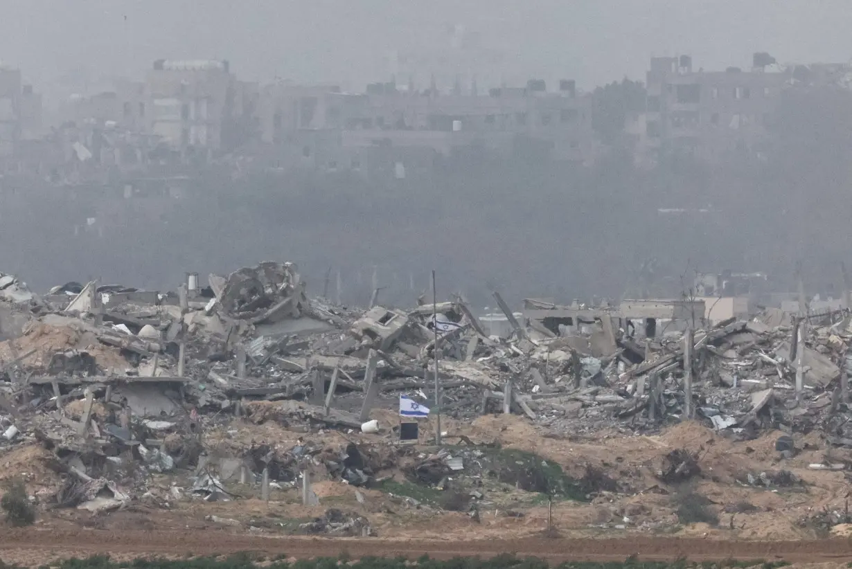 Israeli flags fly next to the rubble of destroyed buildings in Gaza, as seen from southern Israel