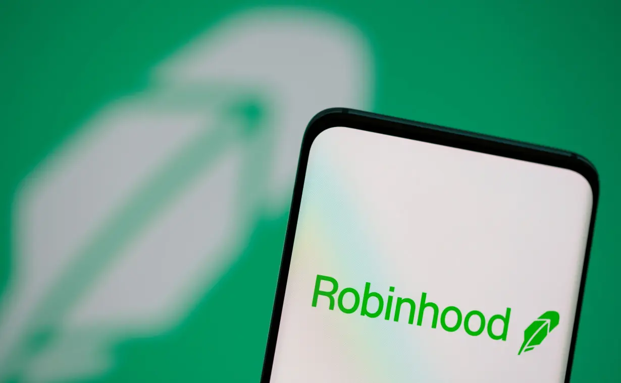 Robinhood logo is seen on a smartphone in front of a displayed logo in this illustration