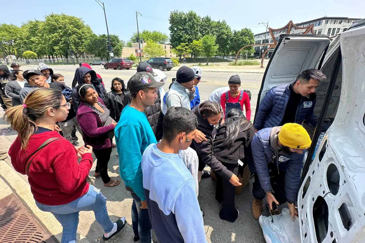 Migrants are given supplies outside the District 12 station of the Chicago Police Department in Chicago