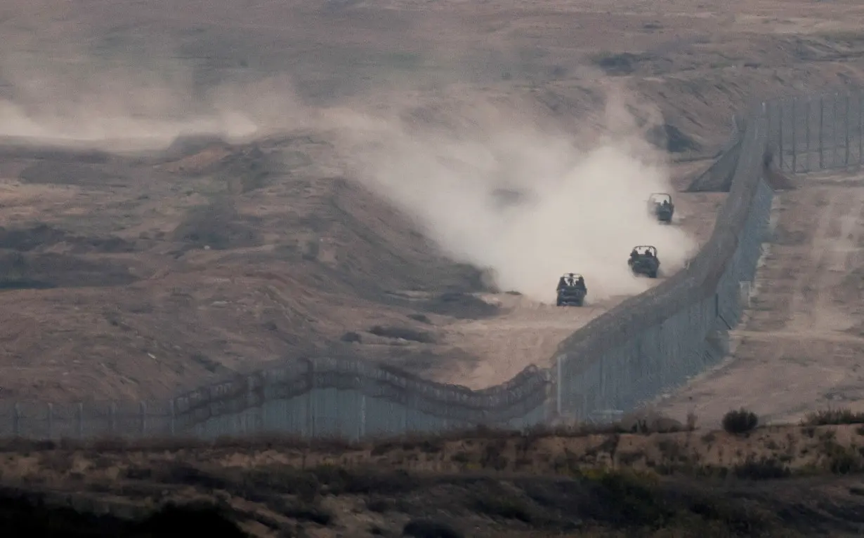 FILE PHOTO: Military vehicles manoeuvre next to a fence, as seen from the Israeli side of the border with Gaza