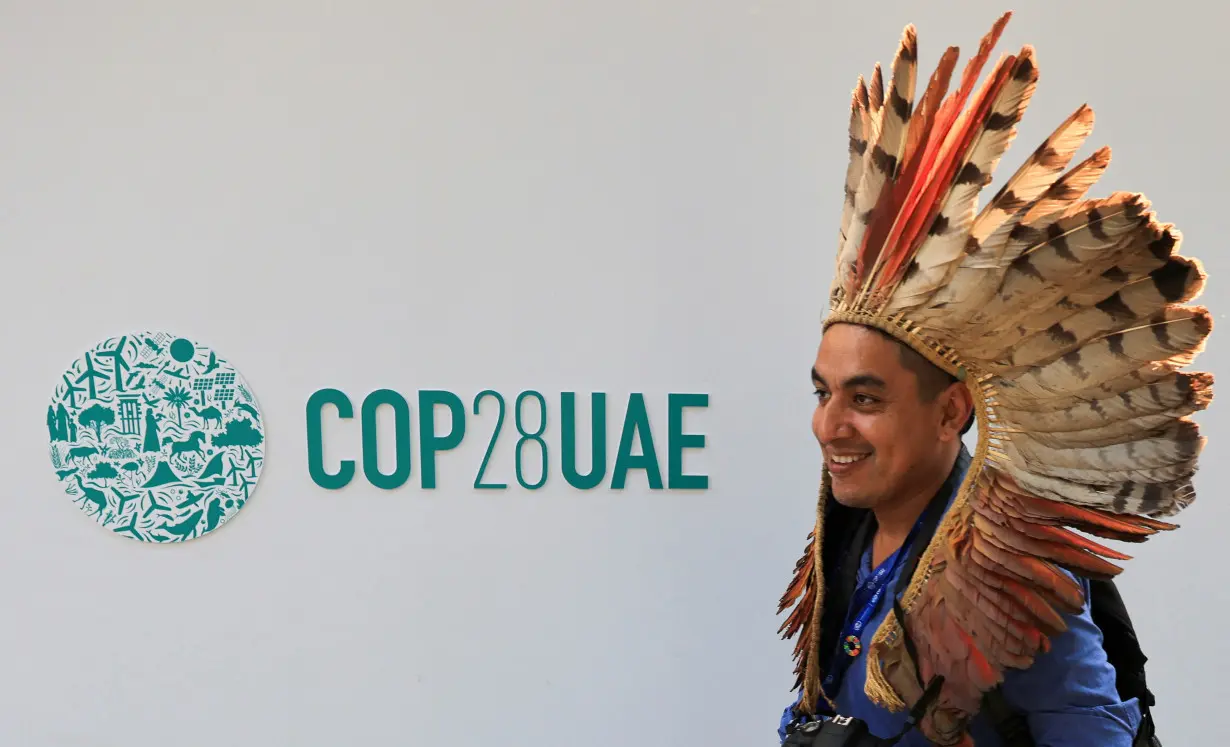 A delegate walks past a logo of the COP28 climate summit in Dubai