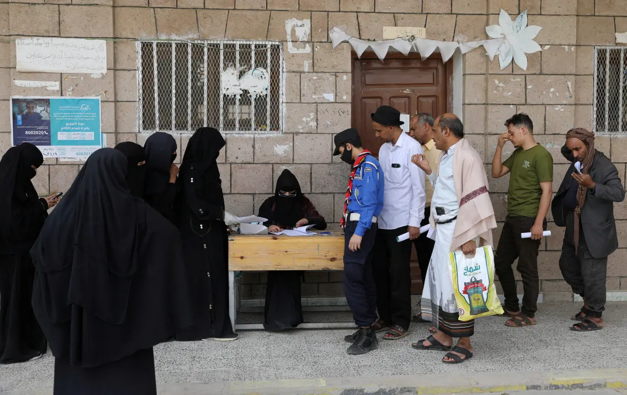 FILE PHOTO: Beneficiaries of World Food Program assistance queue at a food distribution center in Sanaa