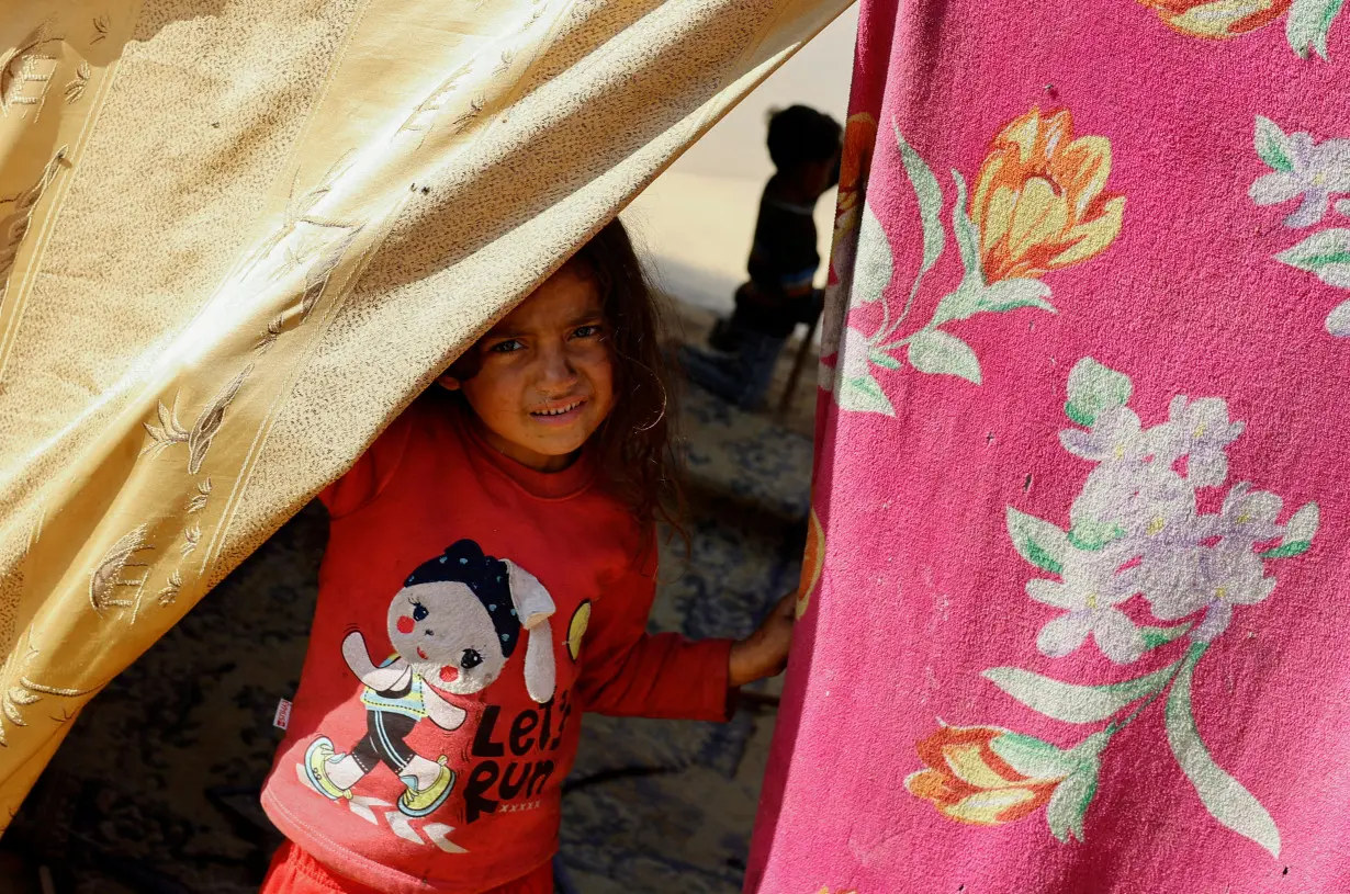 Displaced Palestinians, who fled their houses due to Israeli strikes, shelter in a tent camp near the border with Egypt, in Rafah