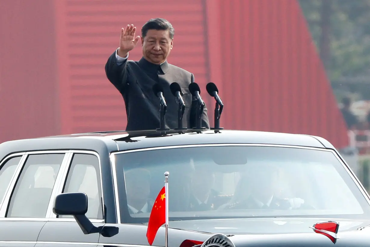 FILE PHOTO: Chinese President Xi Jinping waves from a vehicle as he reviews the troops at a military parade marking the 70th founding anniversary of People's Republic of China