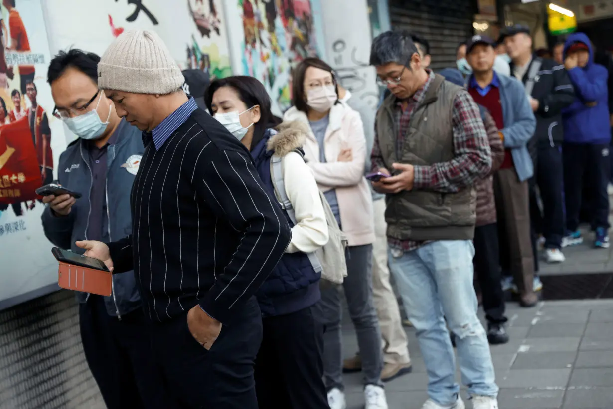 People wait for the opening of the polling station to cast their vote, in Taipei