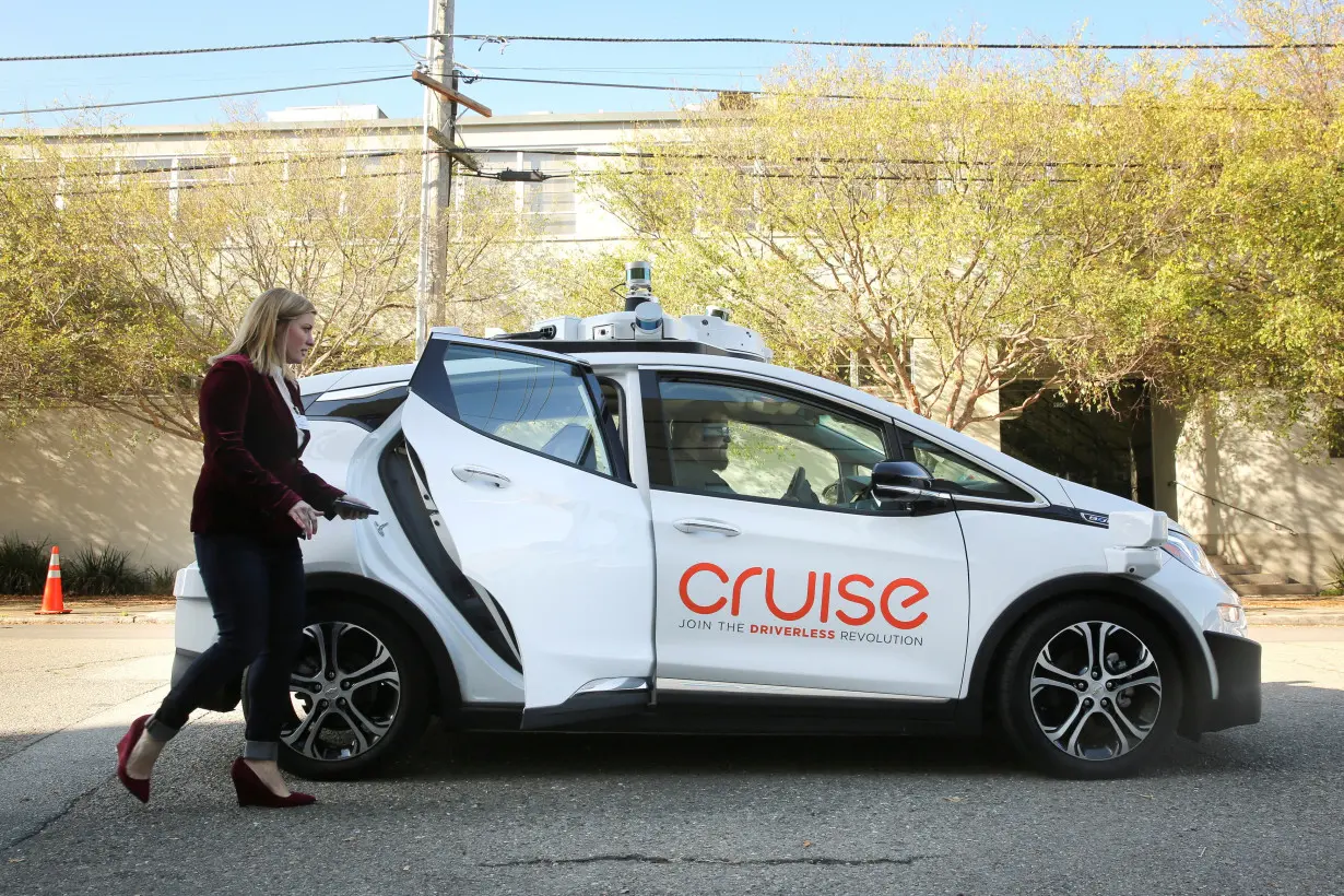 FILE PHOTO: A woman gets in a self-driving Chevy Bolt EV car during a media event by Cruise, GM’s autonomous car unit, in San Francisco