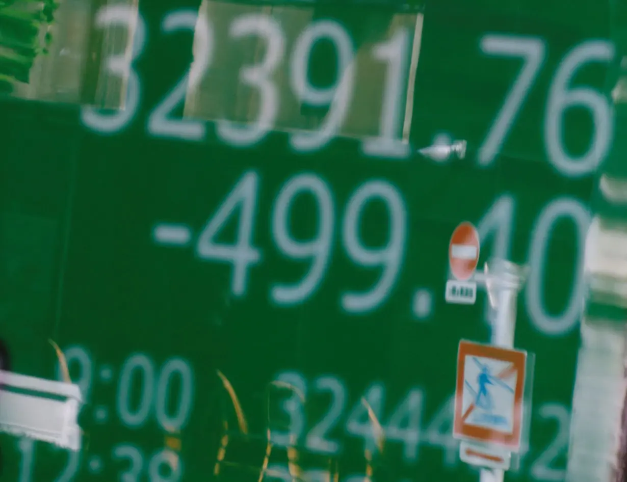 Road signs are reflected on an electric board displaying the Nikkei stock average outside a brokerage in Tokyo