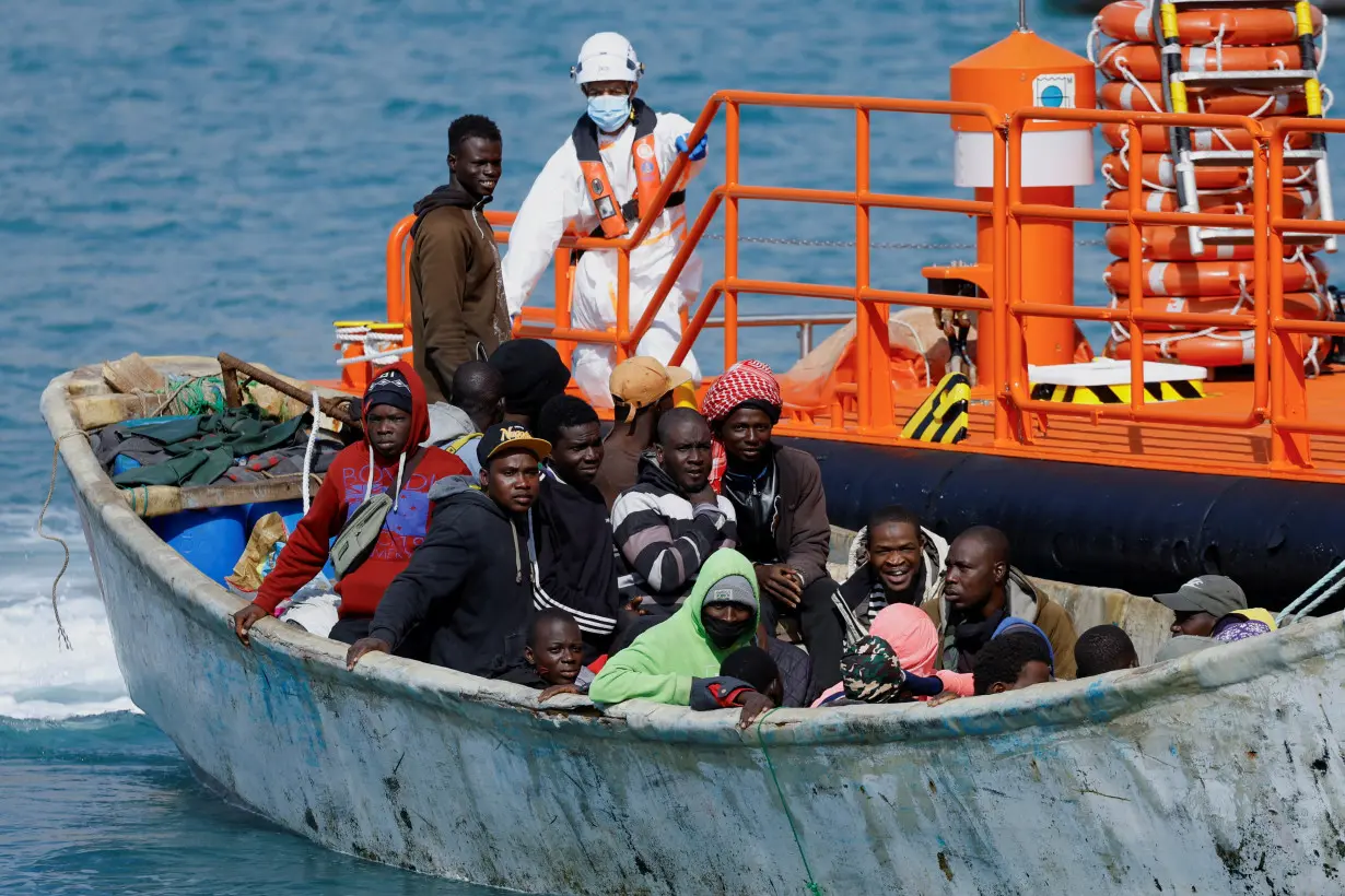A group of migrants wait to disembark from a wooden boat after being rescued by a Spanish coast guard vessel in the port of Arguineguin