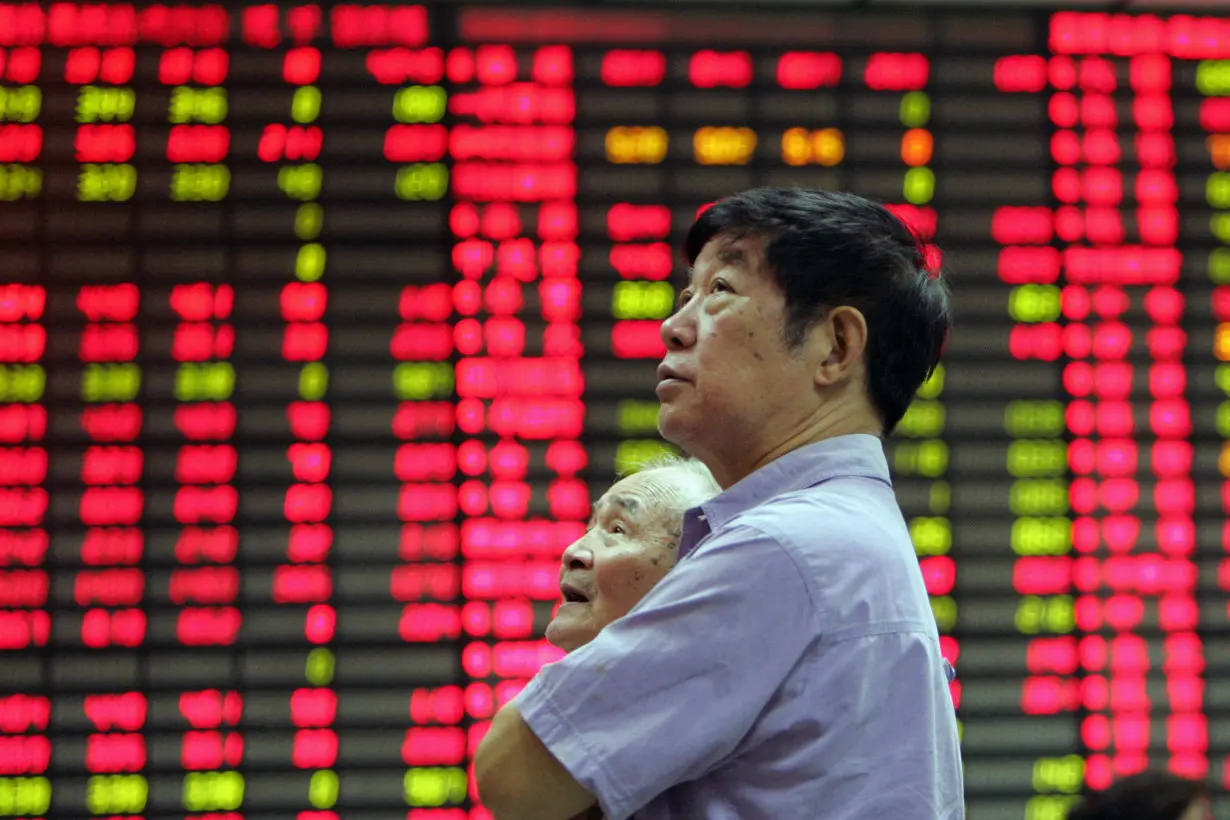 FILE PHOTO: A man stands in front of an electronic stock board in the stock market of Shanghai