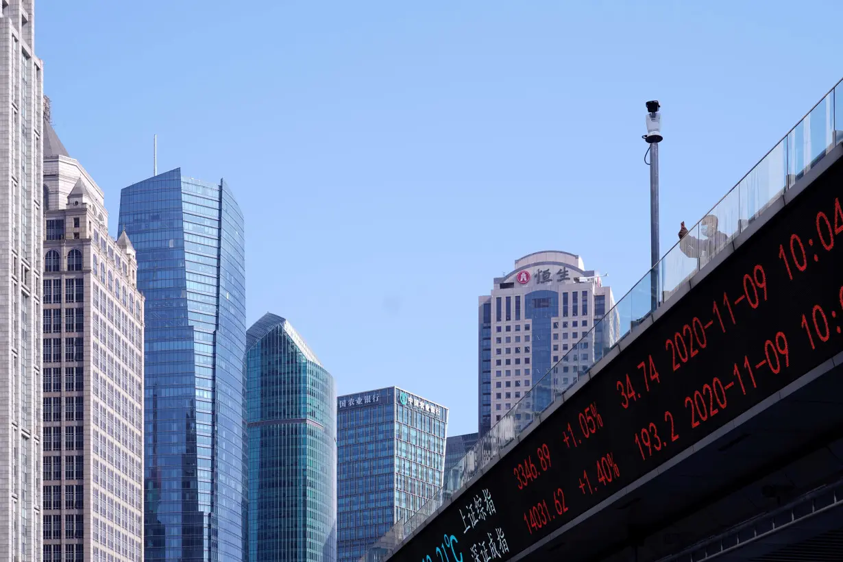 An electronic board showing Shanghai and Shenzhen stock indexes is seen on an overpass at the Lujiazui financial district in Shanghai