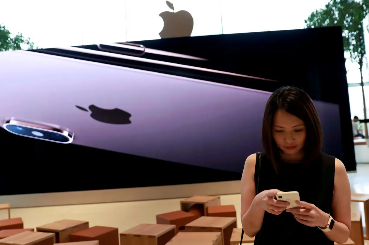 FILE PHOTO: Woman checks her phone at a flagship Apple store at Iconsiam shopping mall in Bangkok