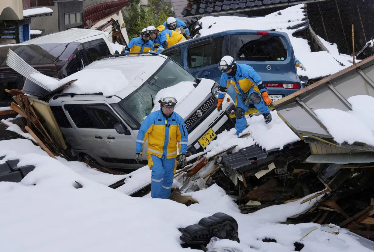 Police officers search for victims in snow-covered residential area devastated by tsunami following earthquake, in Suzu