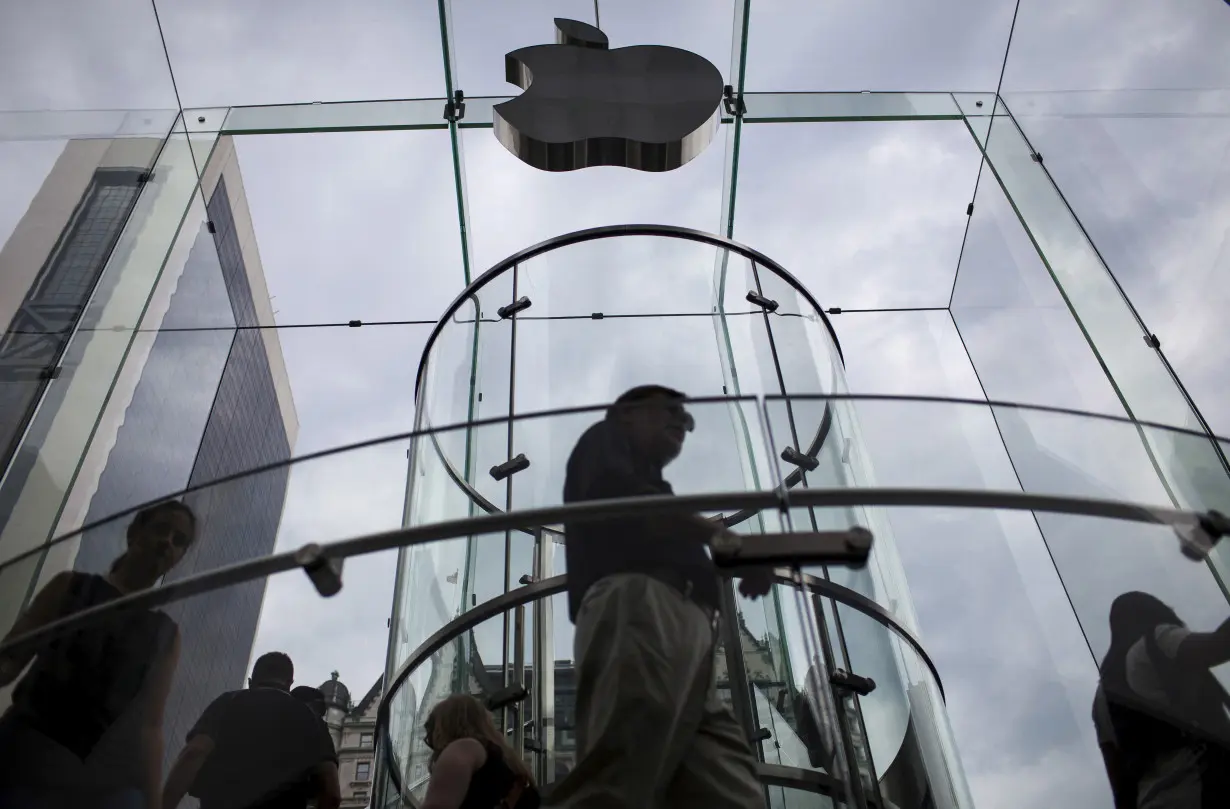 FILE PHOTO: Customers enter the Apple store on 5th Avenue beneath an Apple logo in the Manhattan borough of New York City