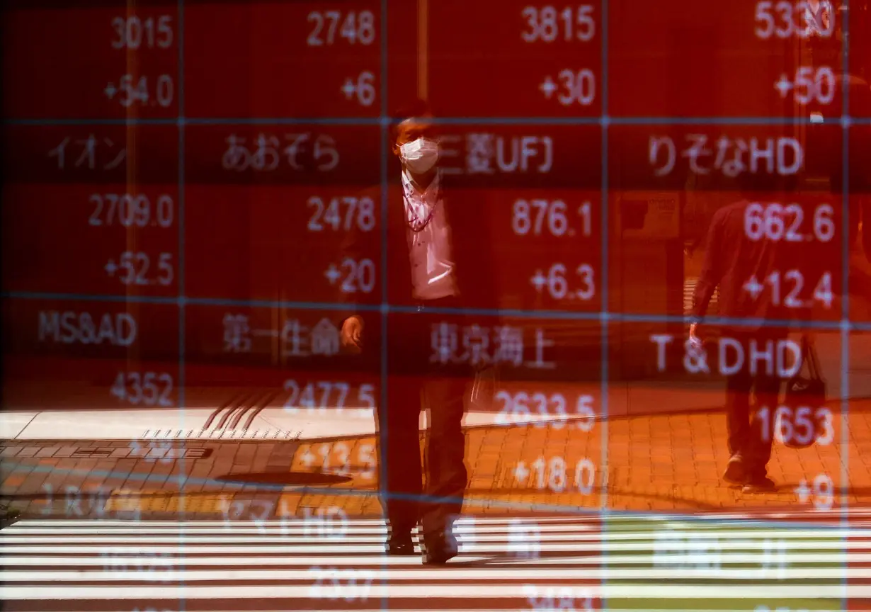 FILE PHOTO: A man is reflected on an electric stock quotation board outside a brokerage in Tokyo