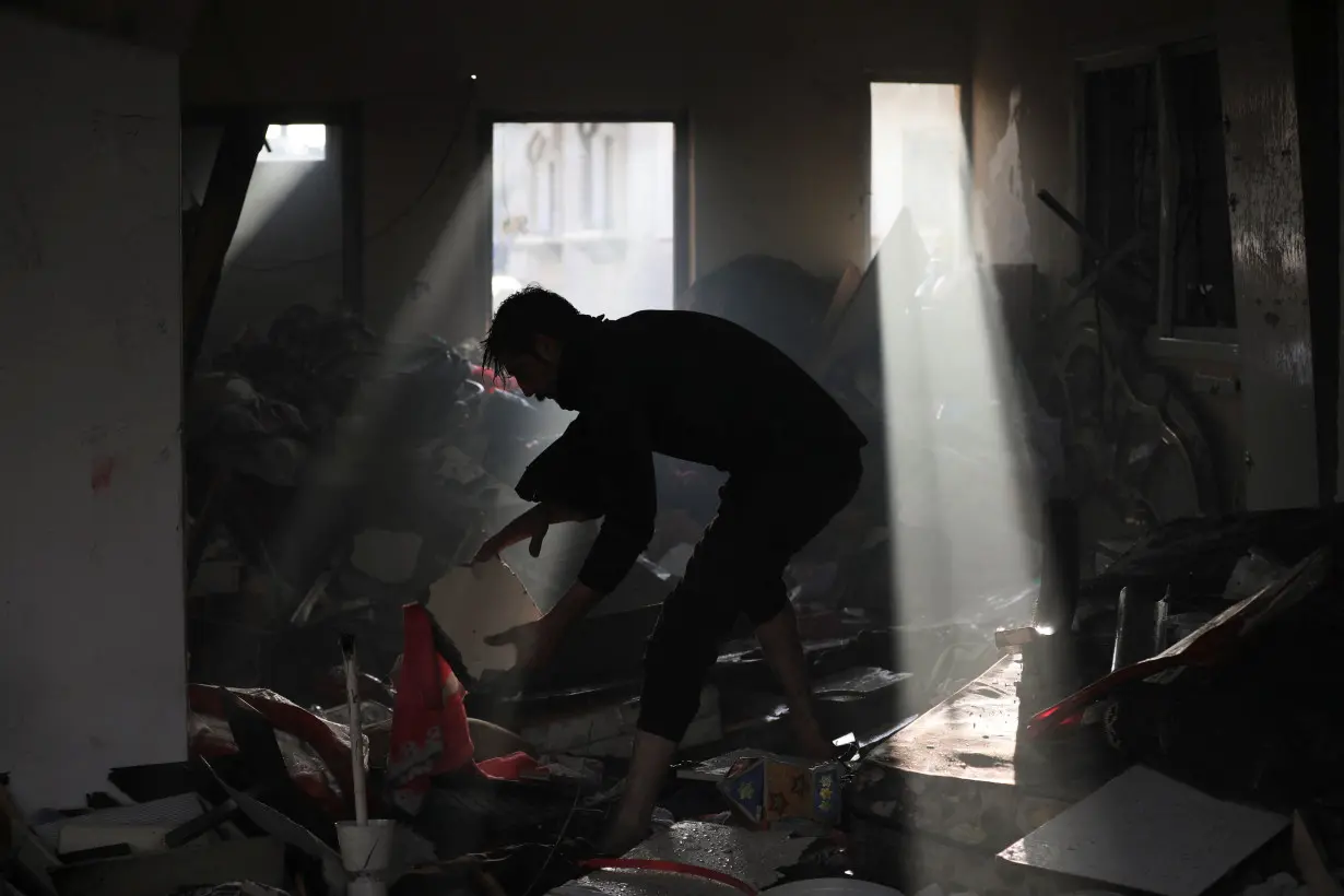 Palestinian picks up debris on the site of an Israeli strike at Maghazi refugee camp in the central Gaza Strip