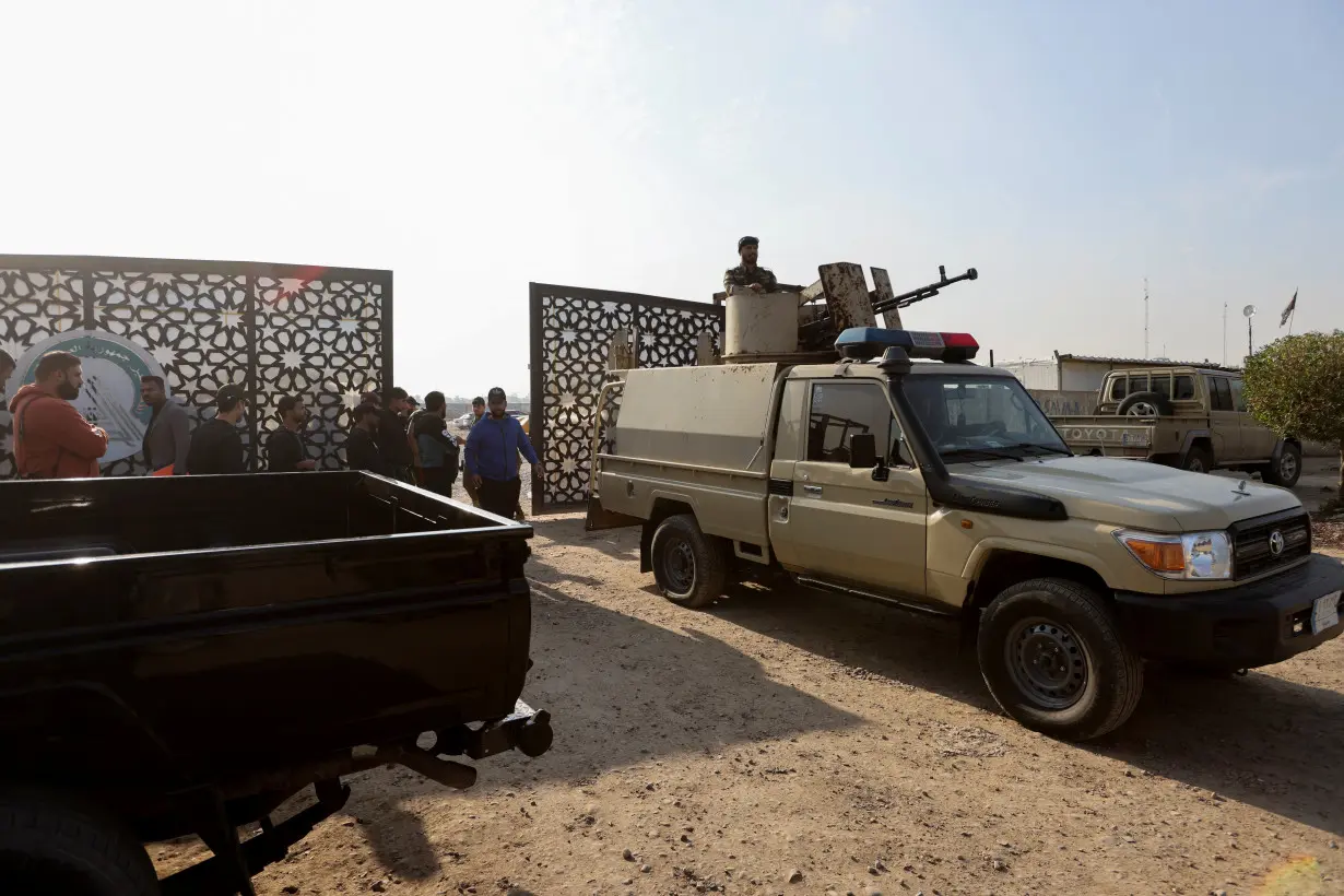 FILE PHOTO: Members of an Iraqi Shi'ite armed group sit in a vehicle after an attack by a drone strike on an Iran-backed militia headquarters in Baghdad