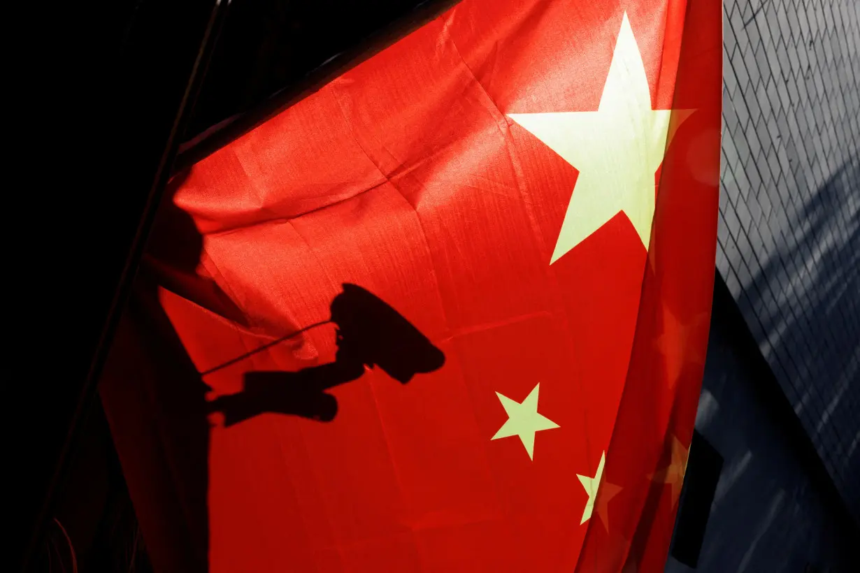 FILE PHOTO: A surveillance camera is silhouetted behind a Chinese national flag in Beijing