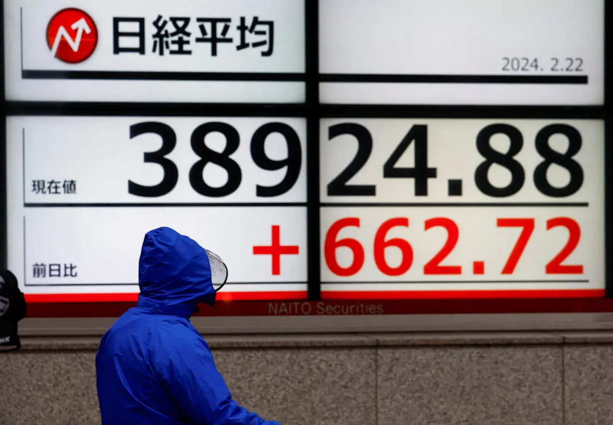 A man walks past electronic screens displaying Japan's Nikkei share average in Tokyo