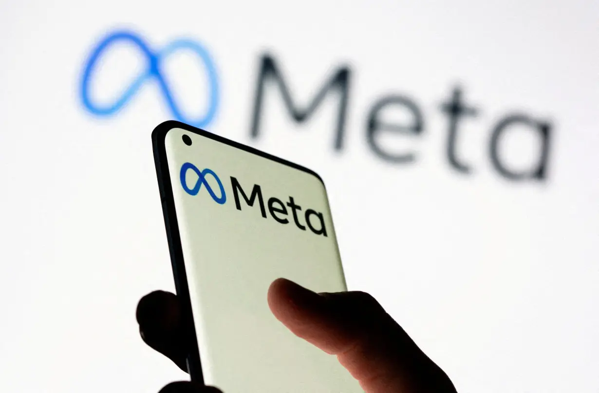 FILE PHOTO: Woman holds smartphone with Meta logo in front of a displayed Facebook's new rebrand logo Meta in this illustration picture