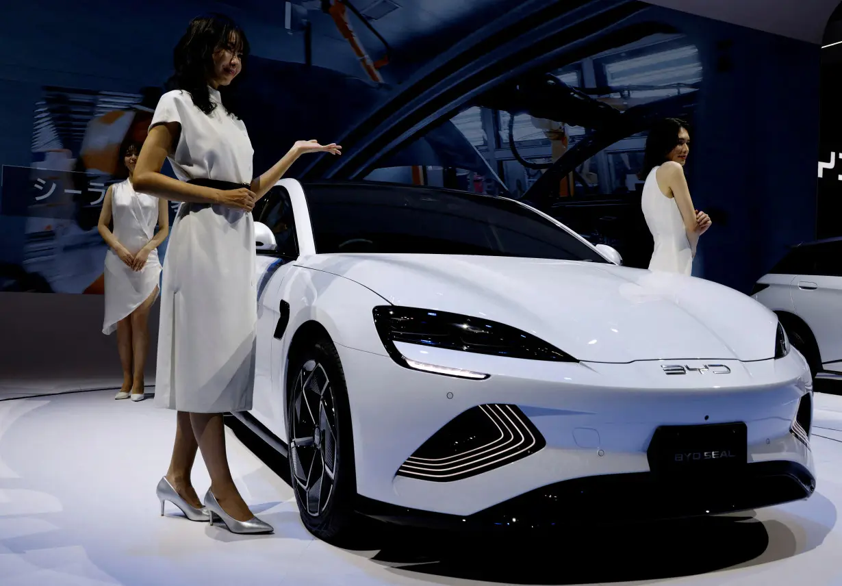 FILE PHOTO: Models pose next to Chinese automobile manufacturer BYD's BYD SEAL during the Japan Mobility Show in Tokyo