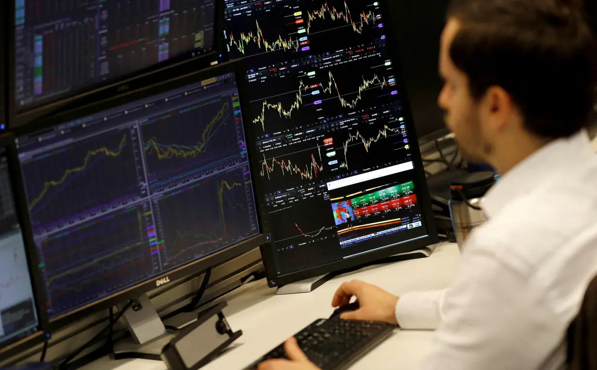 FILE PHOTO: A financial trader works at their desk at CMC Markets in the City of London