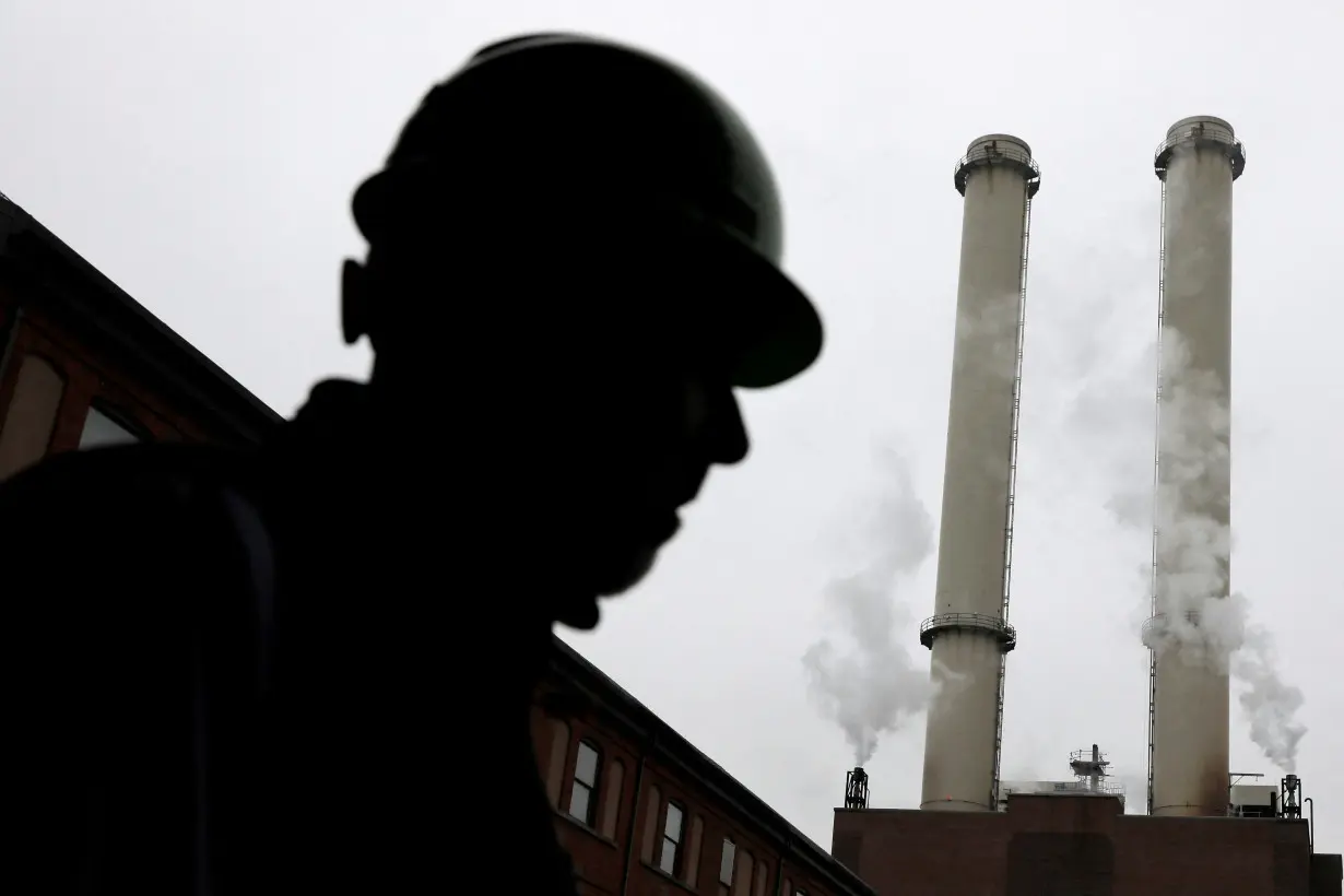 FILE PHOTO: A worker stands near the chimney stacks of a neighbouring factory at IceStone, a manufacturer of recycled glass countertops and surfaces, in New York City