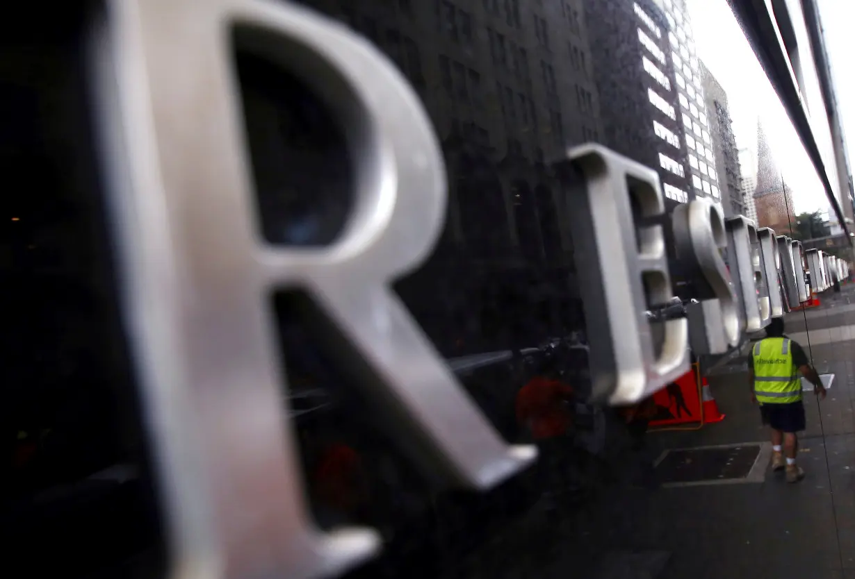 FILE PHOTO: A worker is reflected in a wall of the Reserve Bank of Australia head office in central Sydney, Australia