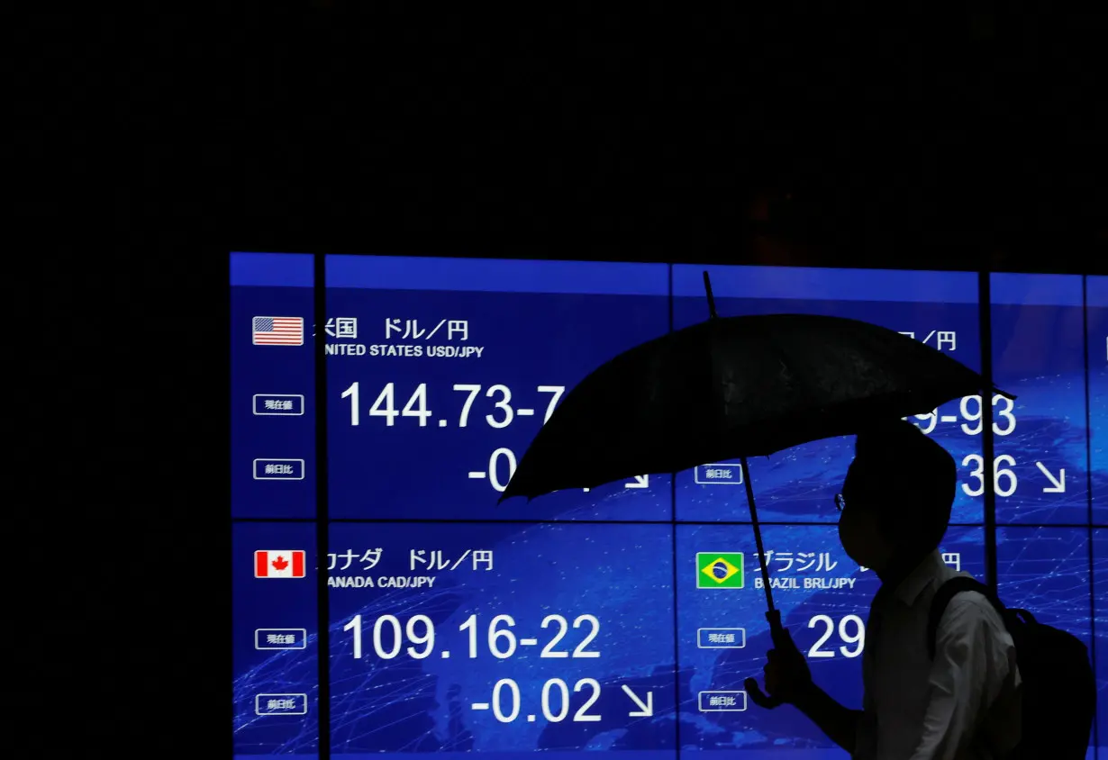 A man walks past an electric monitor displaying the Japanese yen exchange rate against the U.S. dollar and other foreign currencies in Tokyo