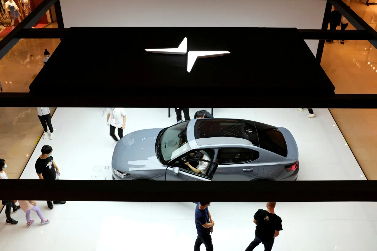 FILE PHOTO: People look at a Polestar 2 electric sedan displayed in a shopping mall in Shanghai