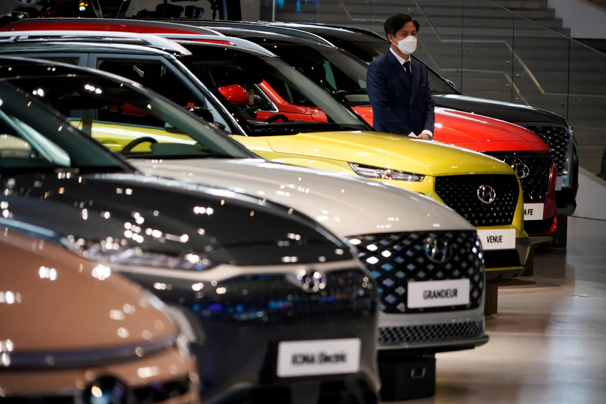 An employee wearing a mask to prevent contracting the coronavirus disease (COVID-19) waits for custormers next to a Hyundai Motor's vehicle at Hyundai Motor Studio in Goyang