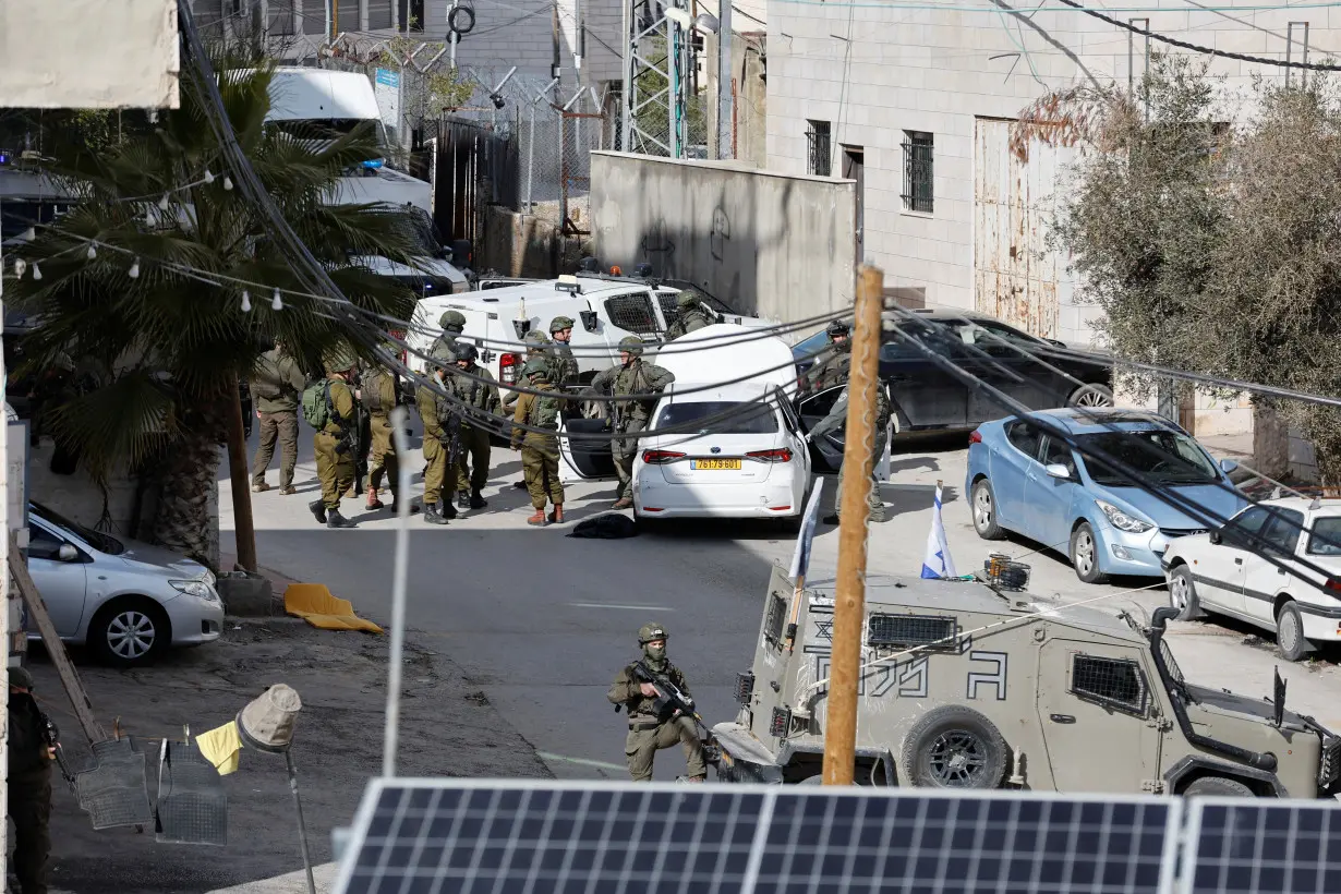 Israeli troops stand guard near a shooting scene in Hebron