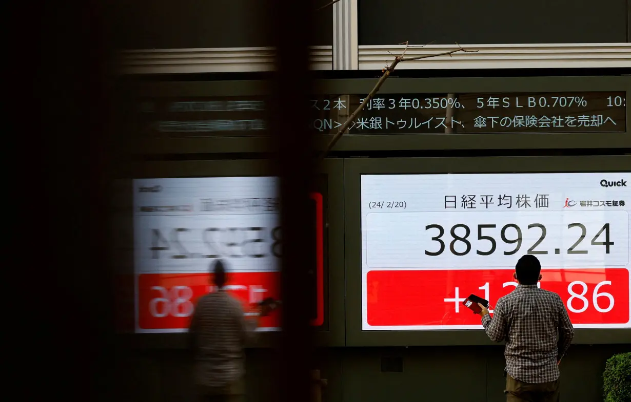 FILE PHOTO: FILE PHOTO: A man looks at an electronic screen displaying Japan's Nikkei share average outside a brokerage in Tokyo