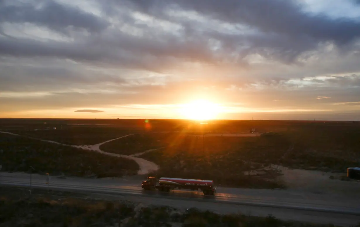 The sun rises behind an oil tanker driving through the Permian Basin in Mentone