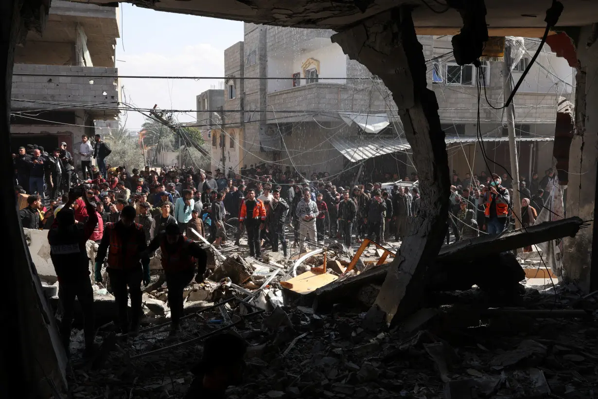 Palestinians inspect the site of an Israeli strike on a house, in Rafah