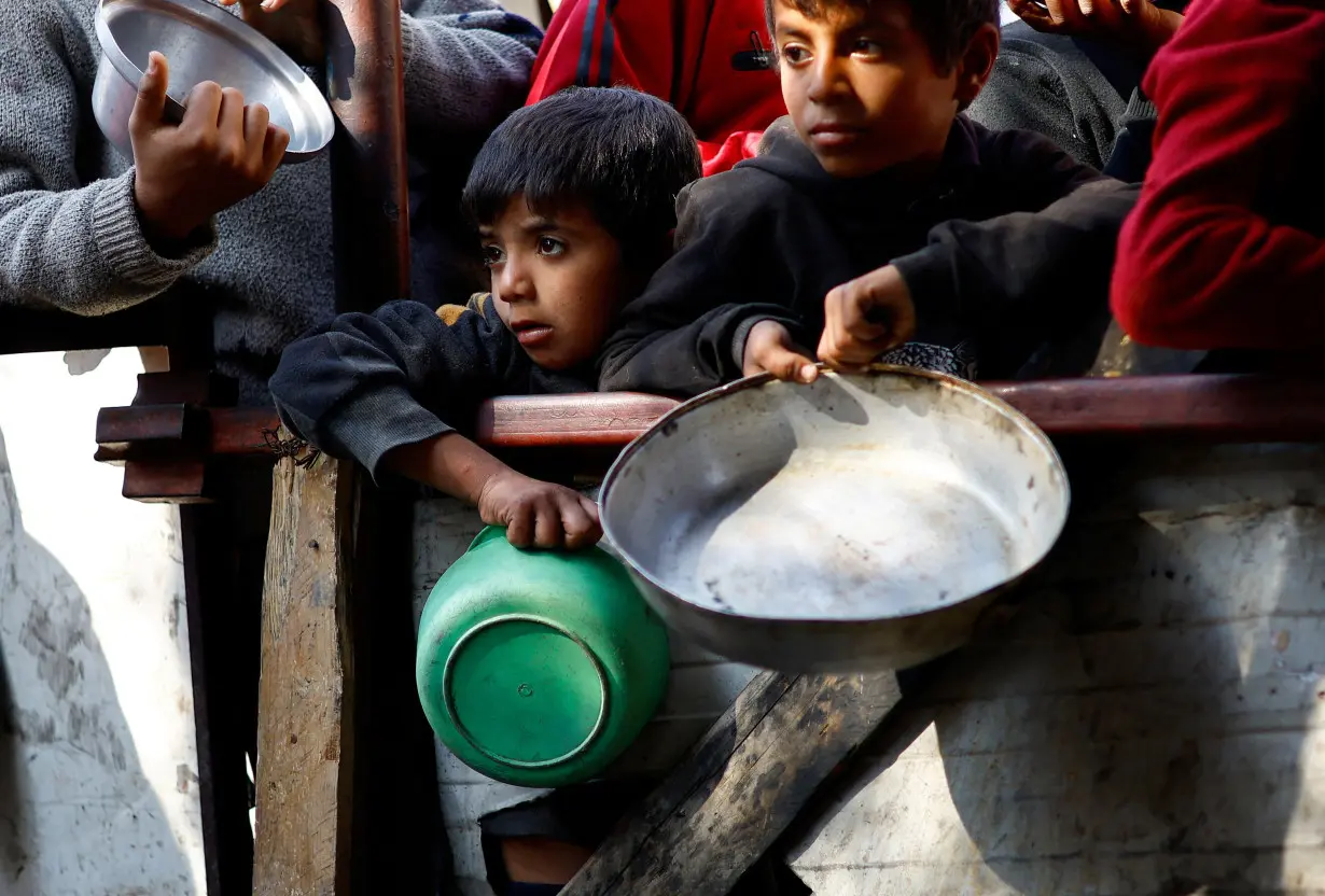 FILE PHOTO: Palestinians wait to receive food amid shortages of food supplies, in Rafah in the southern Gaza Strip